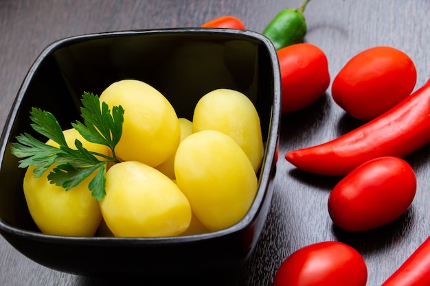 Batatas cozidas com pimenta e tomate em um fundo escuro