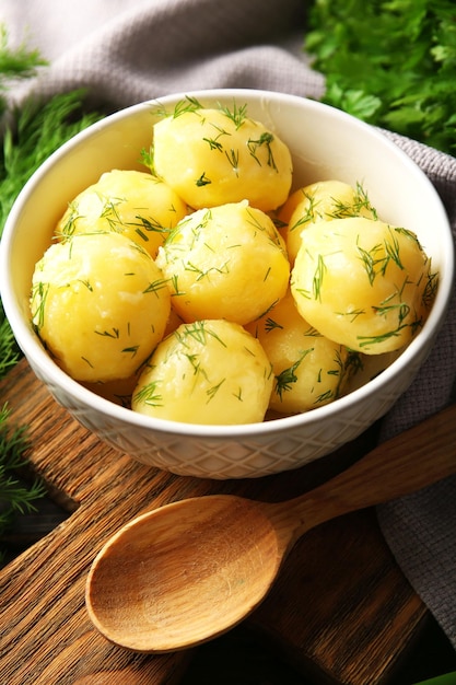 Batatas cozidas com verduras em tigela na mesa close-up