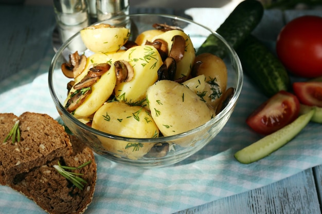 Batatas cozidas jovens em tigela na mesa de madeira fecham