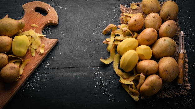 Batatas cruas em um fundo preto de madeira Cozinhar Espaço livre para texto Vista superior