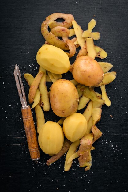 Batatas cruas em um fundo preto de madeira Cozinhar Espaço livre para texto Vista superior