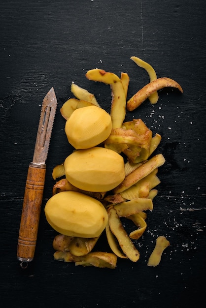 Batatas cruas em um fundo preto de madeira Cozinhar Espaço livre para texto Vista superior