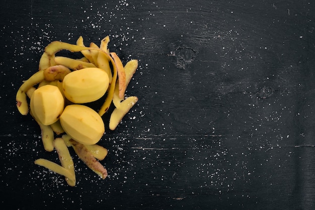 Batatas cruas em um fundo preto de madeira Cozinhar Espaço livre para texto Vista superior