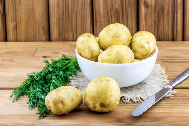 Batatas cruas em uma tigela com uma faca