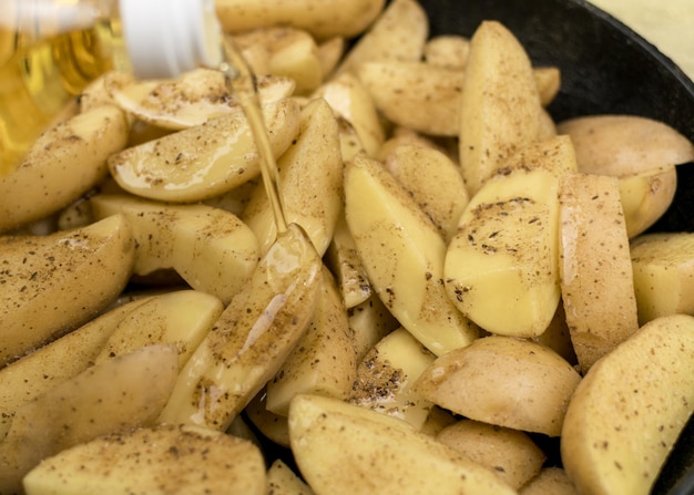 Batatas cruas fatiadas em uma frigideira regada com óleo