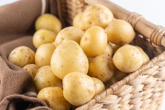 Batatas cruas jovens em uma cesta de vime em um fundo marrom close-up