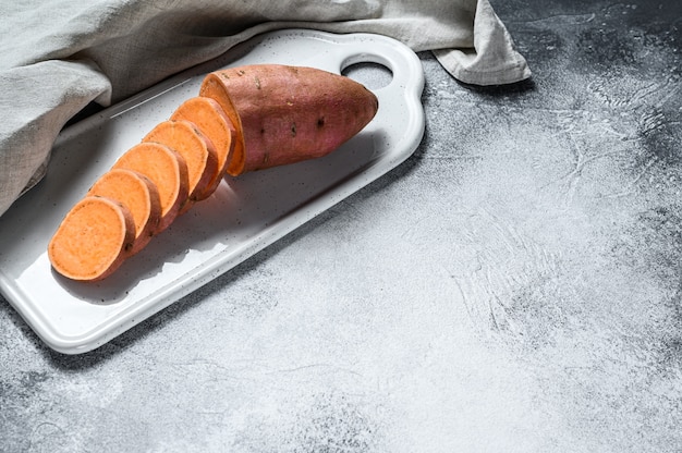 Batatas crudas en una tabla de cortar, ñame orgánico. Cultivar verduras.