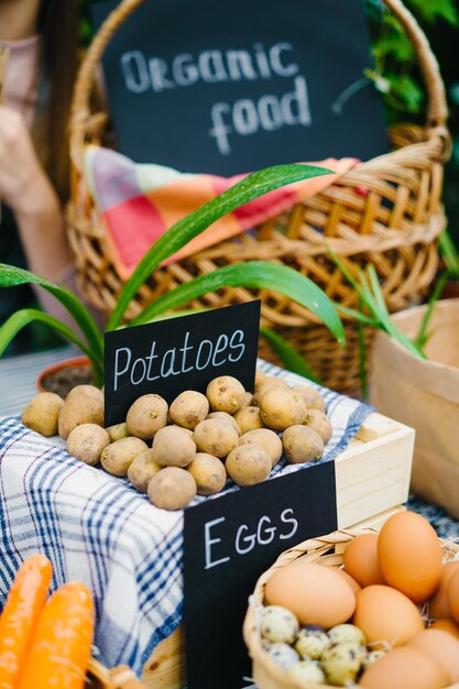 Batatas de alimentos orgânicos úteis e ovos em cestas na mesa no mercado agrícola