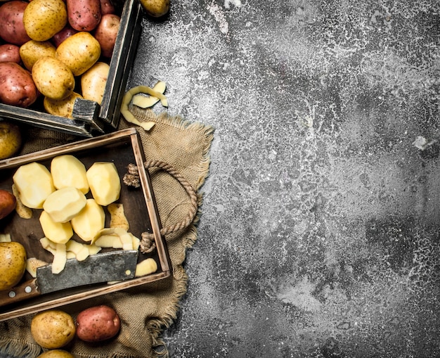 Batatas descascadas em uma placa de madeira. Sobre uma mesa rústica.