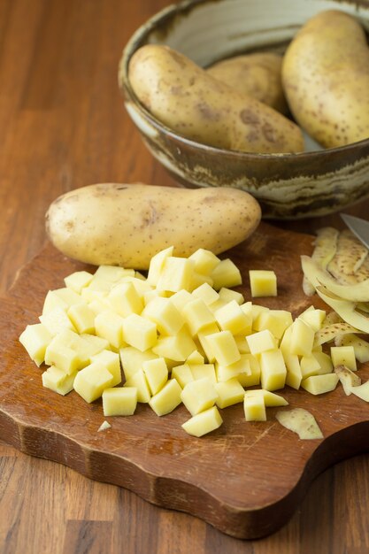 Batatas e batata cortadas na mesa de madeira. Foco seletivo