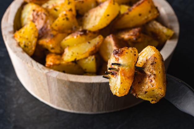 Batatas em uma tigela de madeira na superfície preta