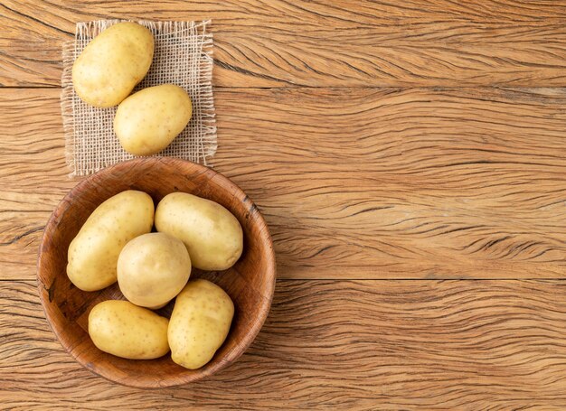 Batatas em uma tigela sobre mesa de madeira com espaço de cópia