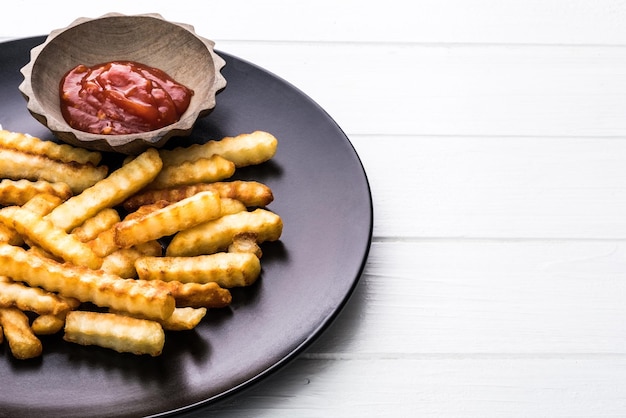 Batatas francesas com ketchup na placa preta