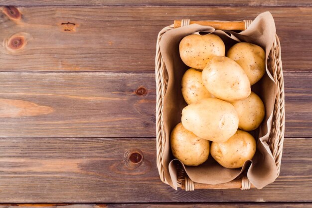 Batatas frescas amarelas em uma cesta em um fundo de madeira. comida vegetariana. vista do topo. copiar spase
