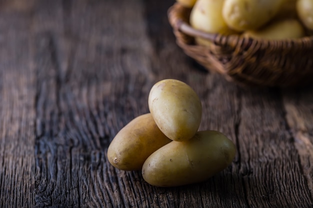 Batatas frescas cruas na cesta na placa de carvalho rústica.