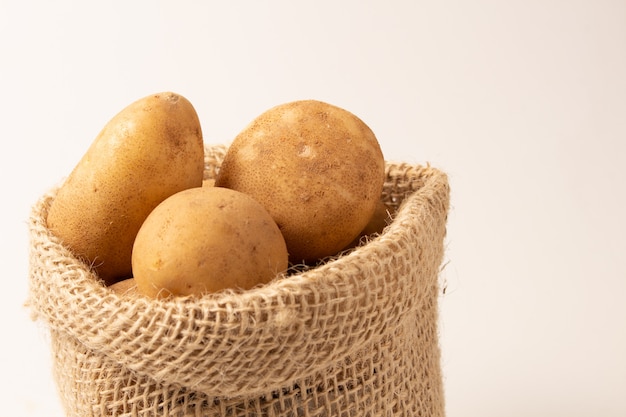 Batatas frescas e cruas em um saco rústico isolado no branco backgroud.