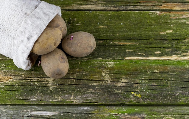 Batatas frescas em um saco em uma superfície de madeira velha