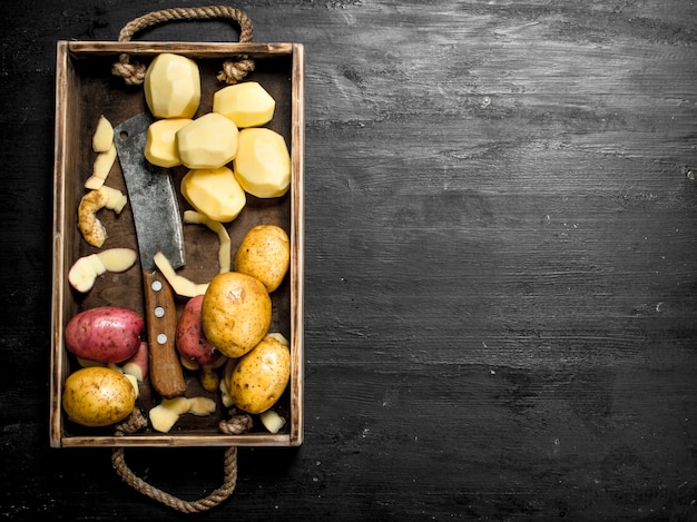 Batatas frescas em uma bandeja. No quadro negro.