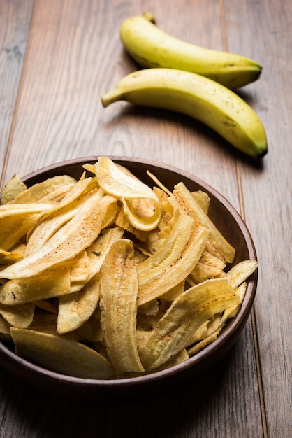 Batatas fritas caseiras saudáveis de Kela ou banana ou wafers servidos sobre uma superfície sombria, foco seletivo