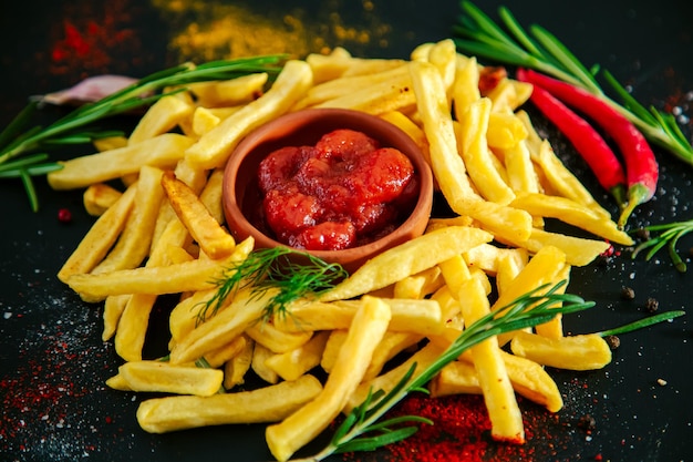 Batatas fritas com ervas e especiarias de ketchup em um fundo preto