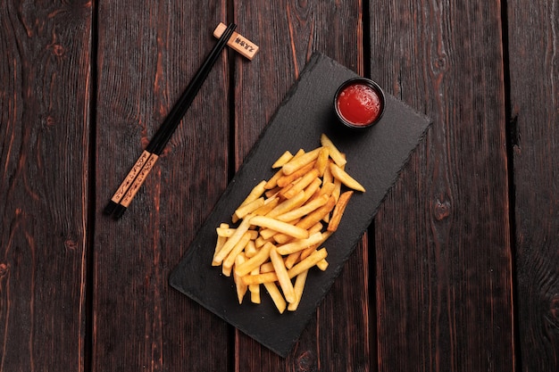 Batatas fritas com ketchup em fundo de madeira escura vista superior fast food e conceito de alimentação pouco saudável