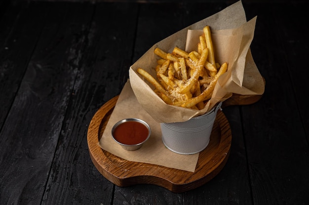 Batatas fritas com molho de tomate em uma mesa de madeira escura