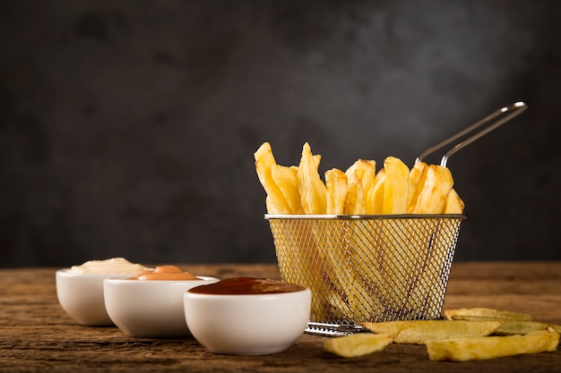 Batatas fritas com molhos em fundo de madeira rústica