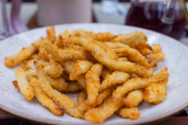 Foto batatas fritas com queijo em pó e molho de maionese servem na placa preta para o fundo ou textura dos alimentos.