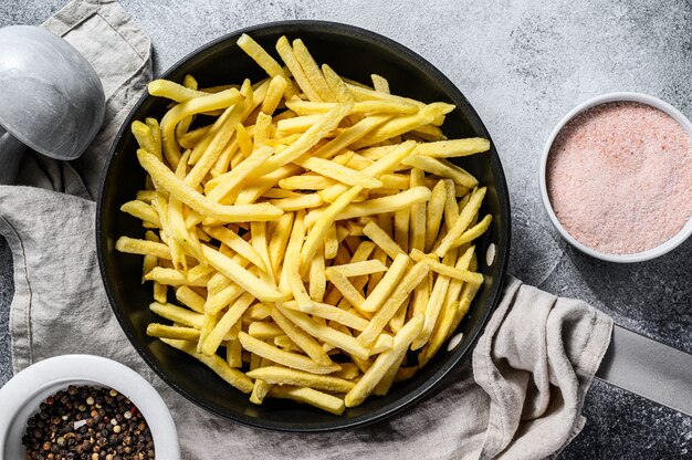 Batatas fritas congeladas em uma frigideira. fundo cinza. vista do topo