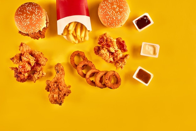 Batatas fritas de hambúrguer de vista superior e frango frito em fundo amarelo Copie o espaço para o seu texto