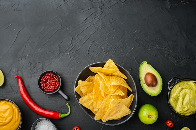 Batatas fritas de nachos mexicanos com molho de queijo e guacamole, em fundo preto, vista de cima ou plano com espaço de cópia para o texto