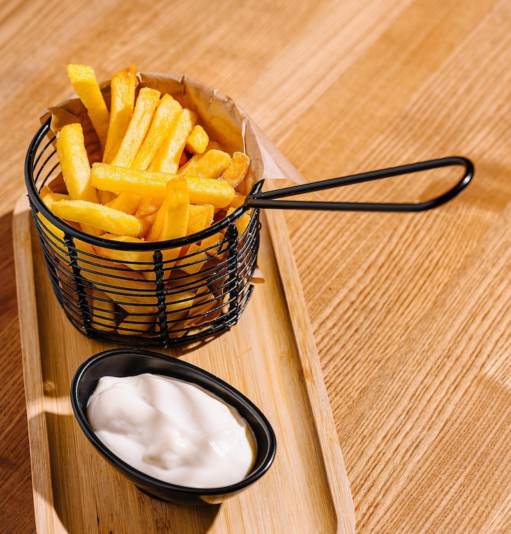 Foto batatas fritas douradas numa cesta de servir com molho