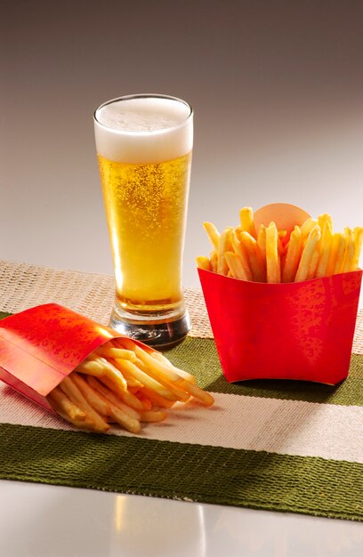 Batatas fritas e chope sobre uma toalha de mesa verde e bege em um fundo gradiente cinza