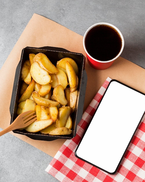 Foto batatas fritas e coca com um telefone em branco