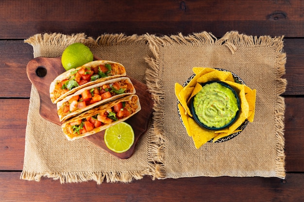 Batatas fritas e tacos de nachos mexicanos com carne e legumes. Tacos, limão e pimenta em placas de madeira. Taco com carne, tomate e ervas