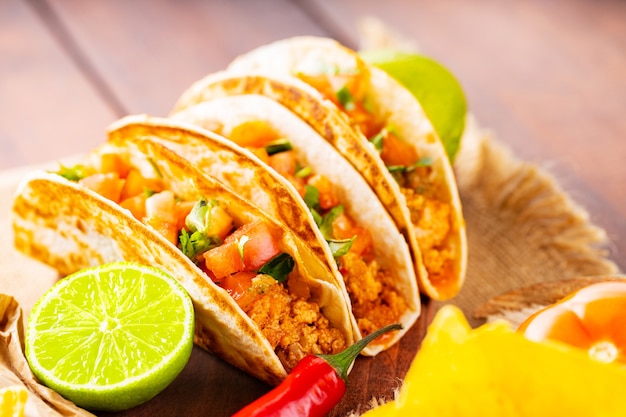 Batatas fritas e tacos de nachos mexicanos com carne e legumes. Tacos, limão e pimenta em placas de madeira. Taco com carne, tomate e ervas