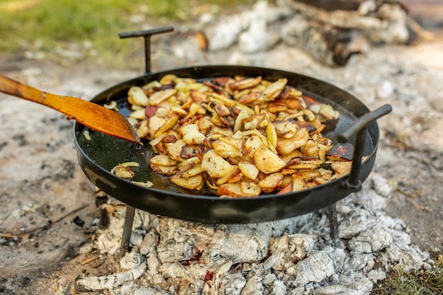 Batatas fritas em fogo na natureza na floresta Conceito de viagem de comida de vegetais