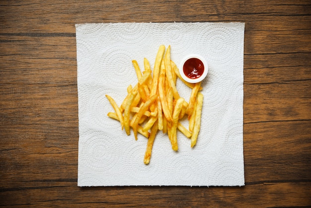 Batatas fritas em papel branco com ketchup em madeira