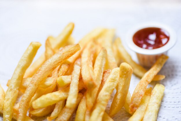 Batatas fritas em papel branco com ketchup na mesa de jantar
