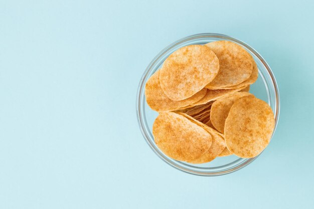 Batatas fritas em tigela de vidro sobre fundo azul Fast food