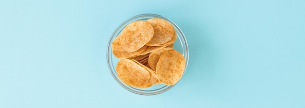 Batatas fritas em tigela de vidro sobre fundo azul Fast food