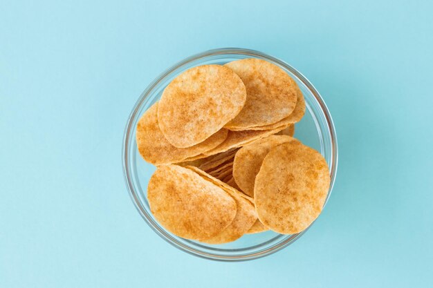 Batatas fritas em tigela de vidro sobre fundo azul Fast food