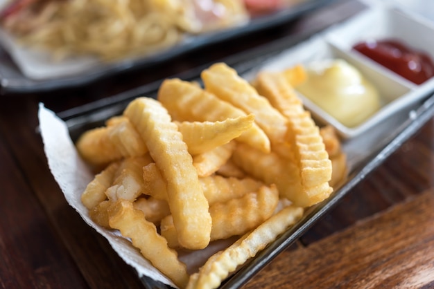 Batatas fritas em tigela sobre fundo de madeira