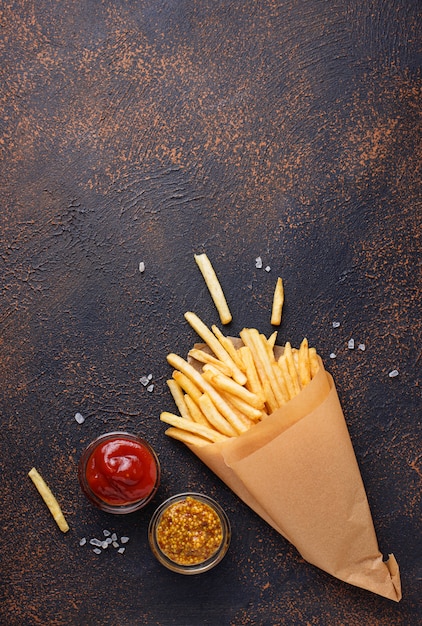 Batatas fritas em um saco de papel com molhos