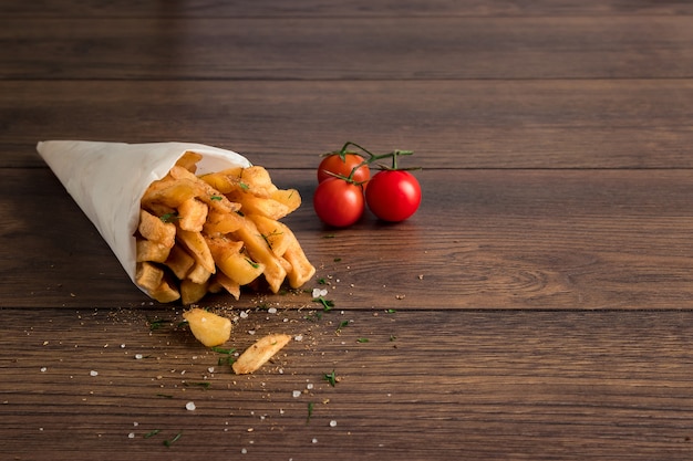 Batatas fritas, em um saco de papel em madeira marrom