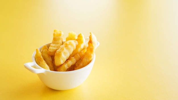 Batatas fritas em uma mesa amarela.