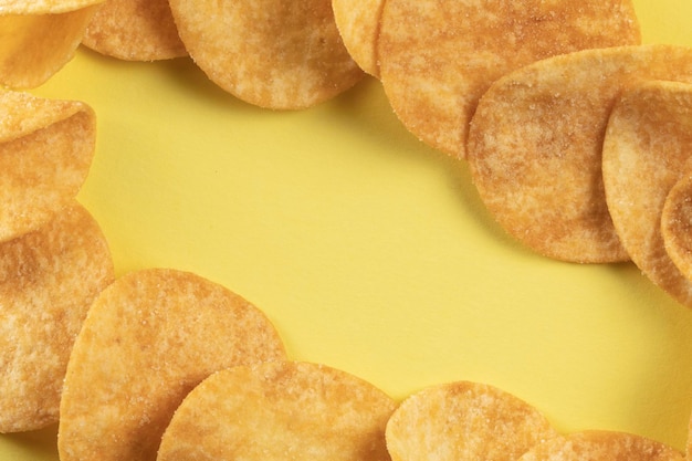 Batatas fritas espalhadas sobre a mesa em um fundo amarelo Alimentos com níveis elevados de colesterol