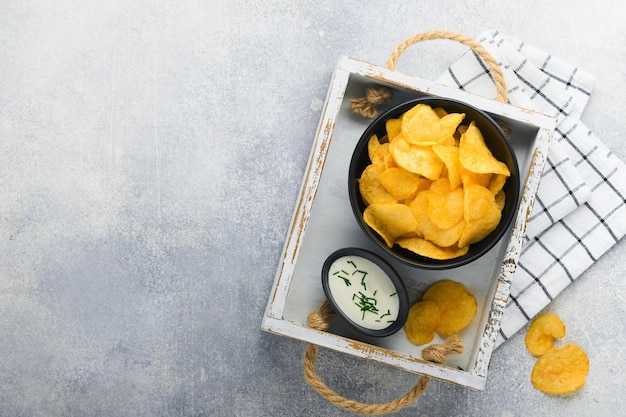 Batatas fritas Fast food Batatas fritas crocantes tigela preta cerâmica com molho de creme de leite e cebolas em carrinho de madeira na mesa de cozinha cinza fundo de concreto Tradição americana Hot BBQ Vista superior