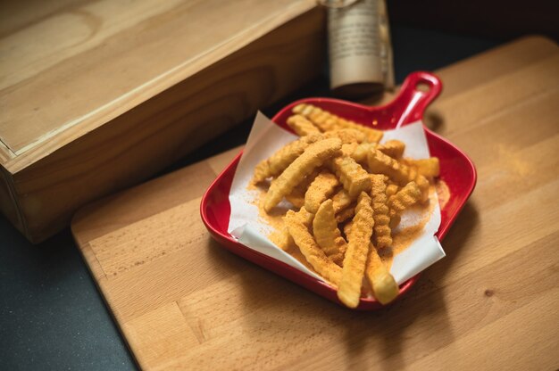 Batatas fritas fechadas com condimentos em fundo escuro