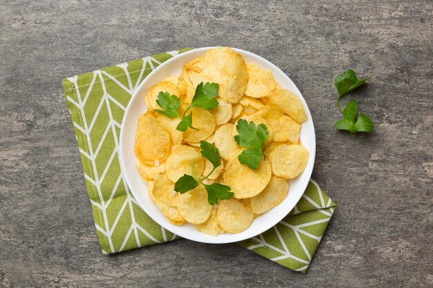 Batatas fritas na tigela com guardanapo em fundo colorido Deliciosas batatas fritas crocantes na tigela Espaço para texto Vista superior